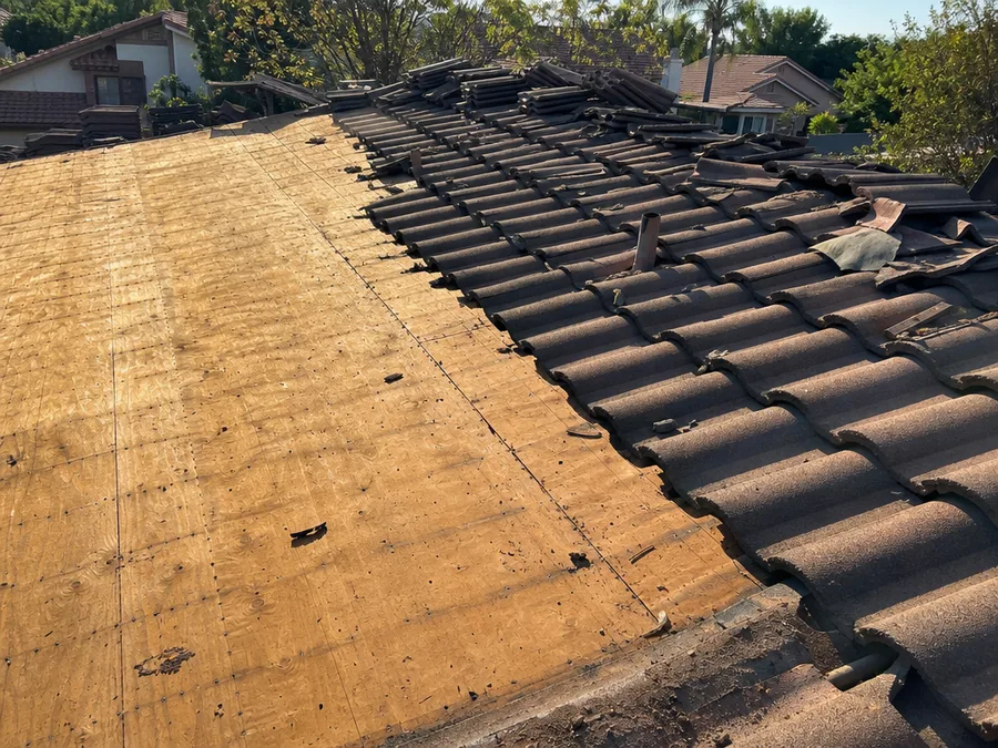 A tear off in progress, half the slope stripped to bare plywood and half still carrying its old covering